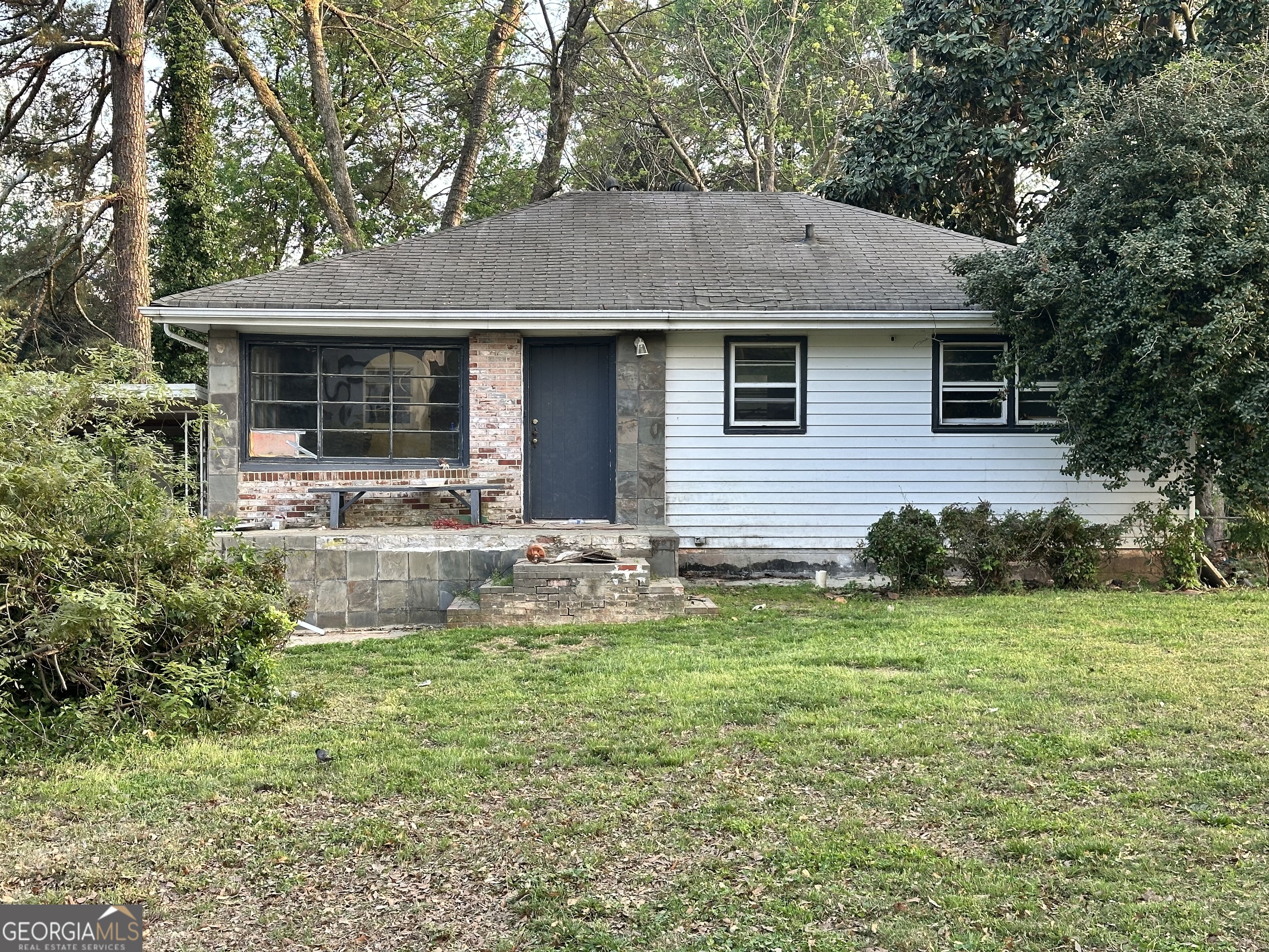 a front view of house with yard and trees all around
