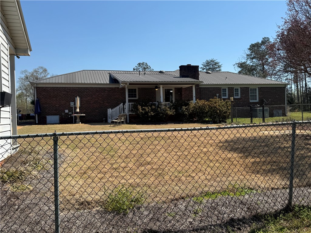 121 Nautical Way Anderson, SC 29625 - Photo 4 of 37 A well-maintained backyard with a brick residence, covered patio, and mature landscaping.