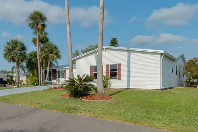 a view of a house with a yard and palm trees