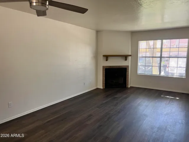 an empty room with wooden floor fireplace and windows