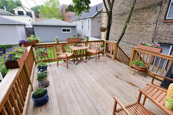 a view of deck with table and chairs potted plants with wooden floor and fence
