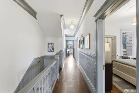 a view of a hallway to a livingroom with wooden floor and stairs