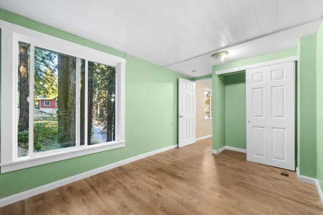 a view of an empty room with window and wooden floor