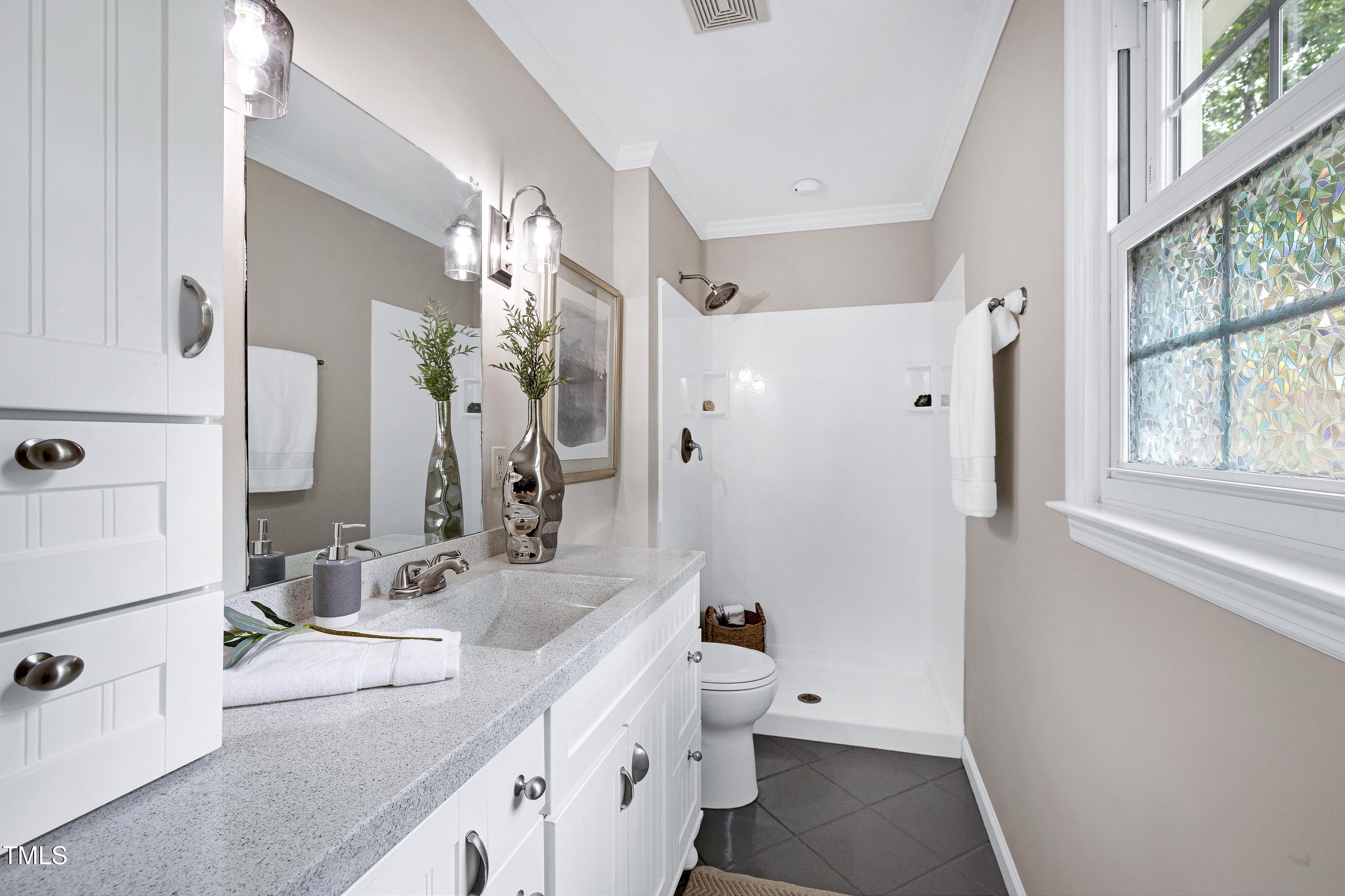 5121 Raintree Road Durham, NC 27712 - Photo 30 of 59 a spacious bathroom with a double vanity sink a mirror and a shower
