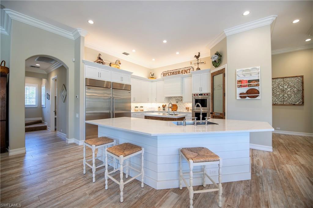 6610 Sable Ridge Lane Naples, FL 34109 - Photo 11 of 50 a kitchen with stainless steel appliances granite countertop a table chairs refrigerator and sink