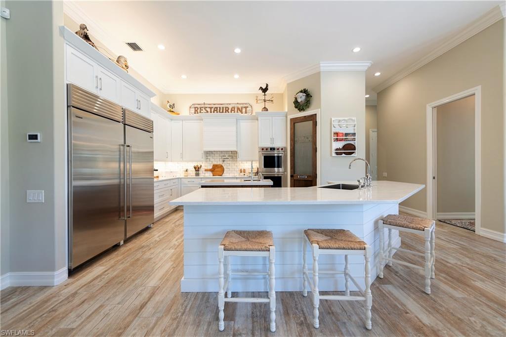 6610 Sable Ridge Lane Naples, FL 34109 - Photo 35 of 50 a kitchen with stainless steel appliances granite countertop a table chairs and a refrigerator