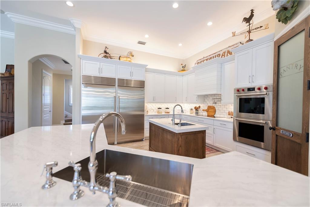 6610 Sable Ridge Lane Naples, FL 34109 - Photo 37 of 50 a large kitchen with kitchen island a counter top space a sink stainless steel appliances and cabinets
