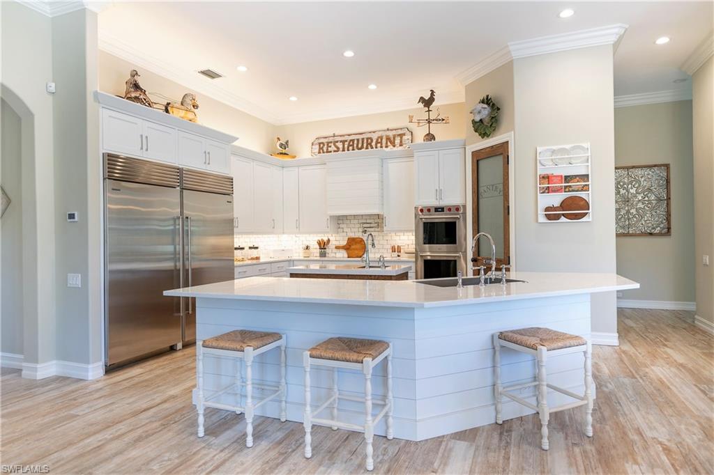 6610 Sable Ridge Lane Naples, FL 34109 - Photo 38 of 50 a kitchen with stainless steel appliances granite countertop a table chairs stove and refrigerator