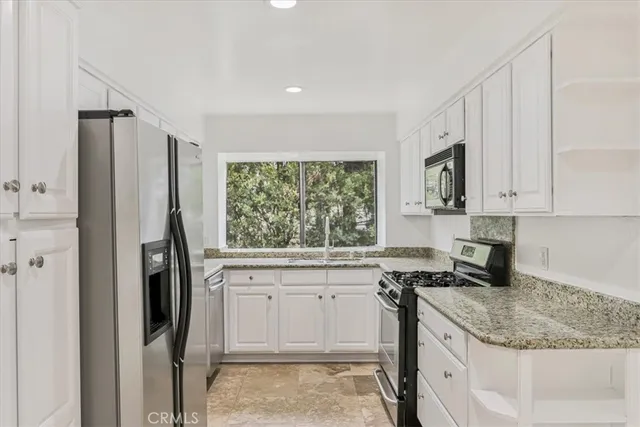 a kitchen with stainless steel appliances granite countertop a refrigerator sink and stove