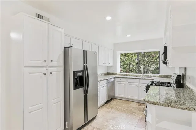 a kitchen with stainless steel appliances granite countertop a refrigerator sink and stove
