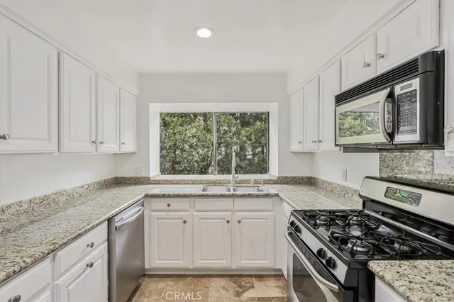 a kitchen with stainless steel appliances granite countertop a sink stove and cabinets