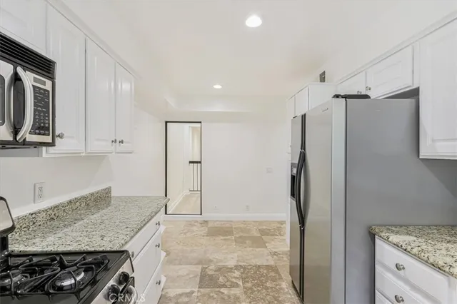 a kitchen with stainless steel appliances granite countertop a refrigerator and a stove top oven