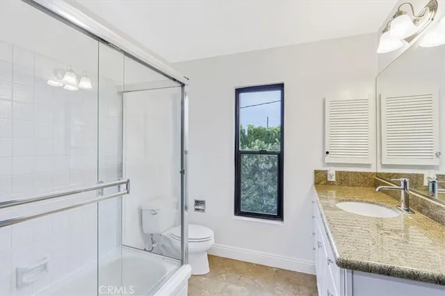 a bathroom with a granite countertop sink toilet and shower