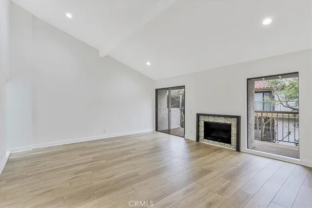 a view of an empty room with wooden floor fireplace and a window