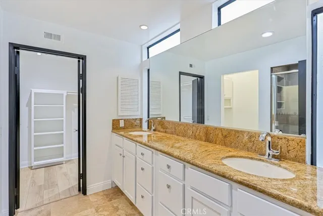 a bathroom with a granite countertop double vanity sink and a mirror