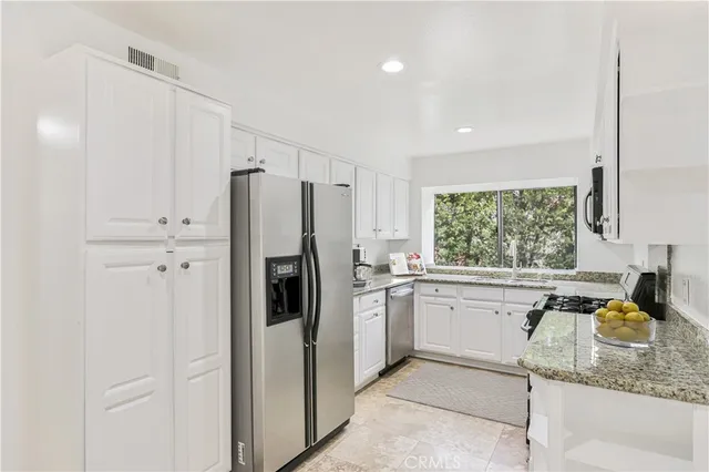 a kitchen with stainless steel appliances granite countertop a refrigerator sink and stove