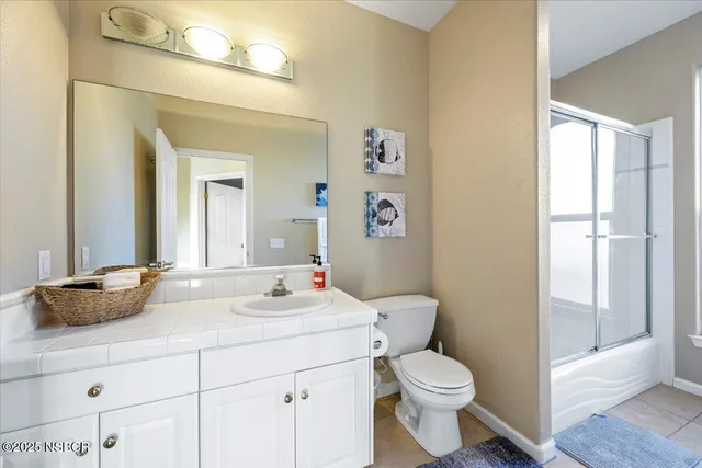 a bathroom with a granite countertop sink mirror vanity and toilet