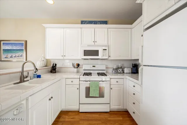 a kitchen with white cabinets and white appliances