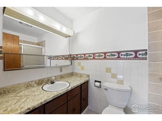 a bathroom with a granite countertop sink a toilet a mirror and shower