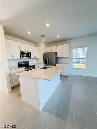 a large kitchen with kitchen island a stove a sink a refrigerator and a refrigerator