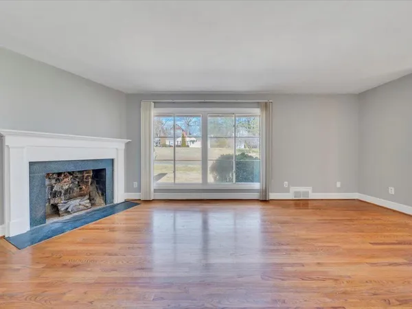 a view of empty room with wooden floor and fireplace
