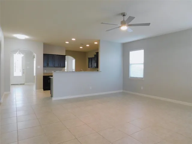 an empty room with chandelier fan and windows