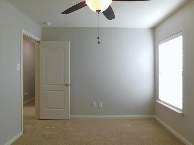 an empty room with a window and a fan