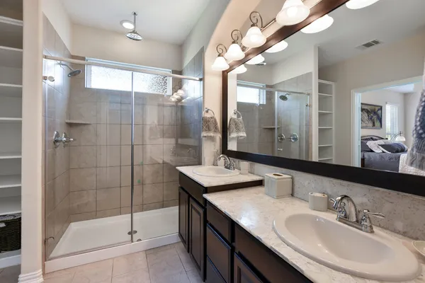 a bathroom with a double vanity sink mirror and shower