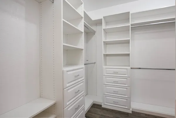 a walk in closet with white cabinet