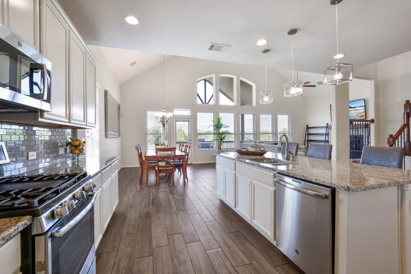 a kitchen with stainless steel appliances granite countertop a stove and a wooden floors