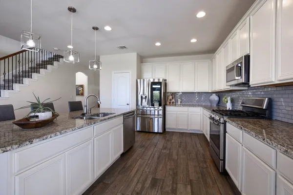 a large kitchen with granite countertop lots of counter top space a sink and stainless steel appliances