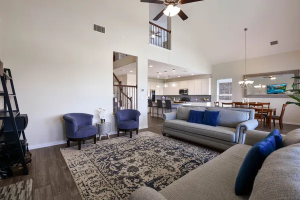 a living room with furniture kitchen view and a chandelier