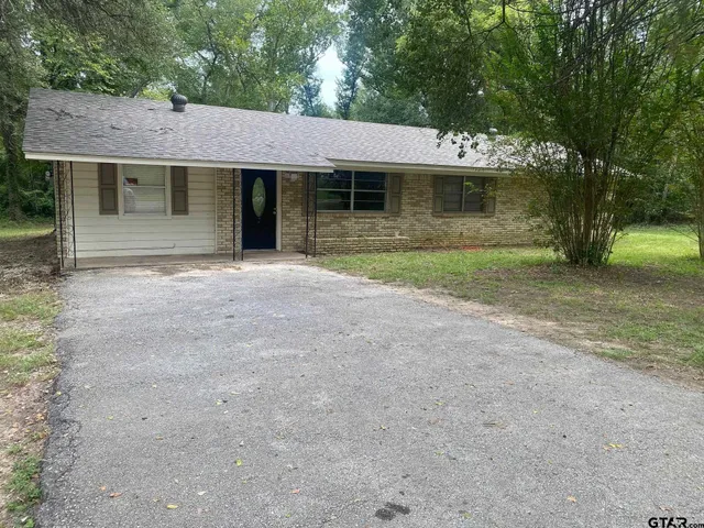 a front view of a house with a garden and trees
