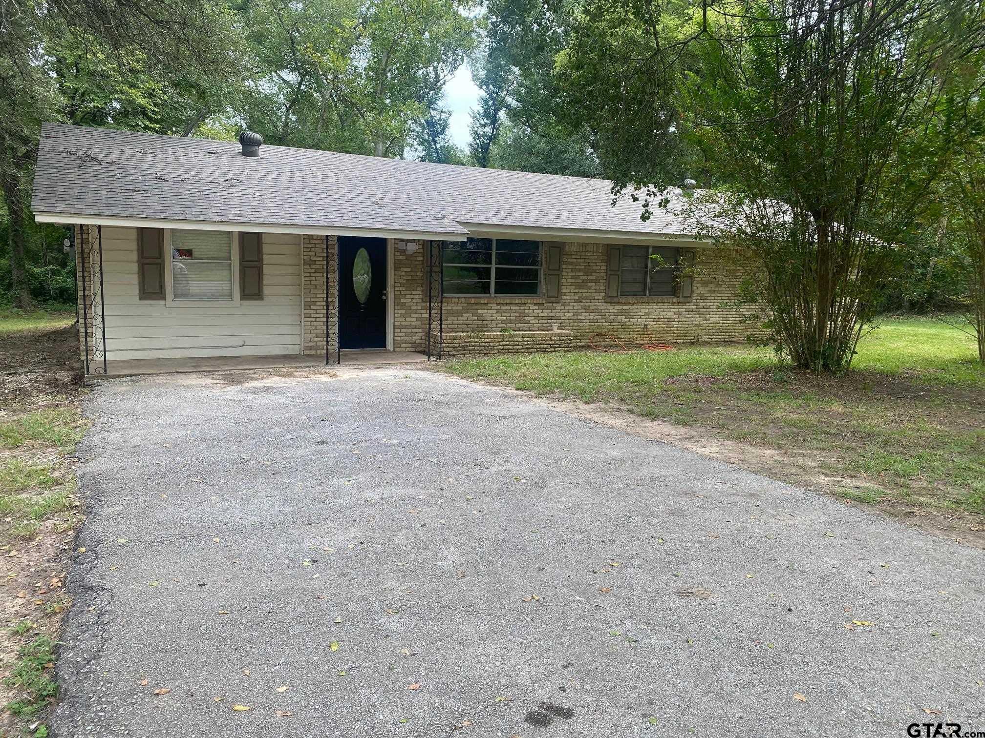 a front view of a house with a garden and trees