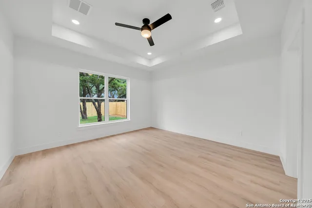 an empty room with windows and ceiling fan