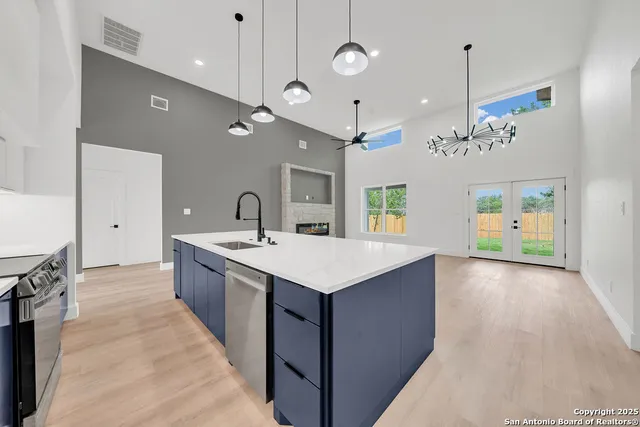 a large kitchen with kitchen island a island a sink stainless steel appliances and a chandelier