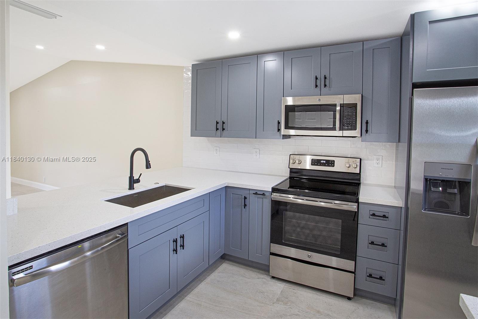 9431 Boca Cove Circle, Unit 1009 Boca Raton, FL 33428 - Photo 2 of 30 a kitchen with white cabinets stainless steel appliances and sink