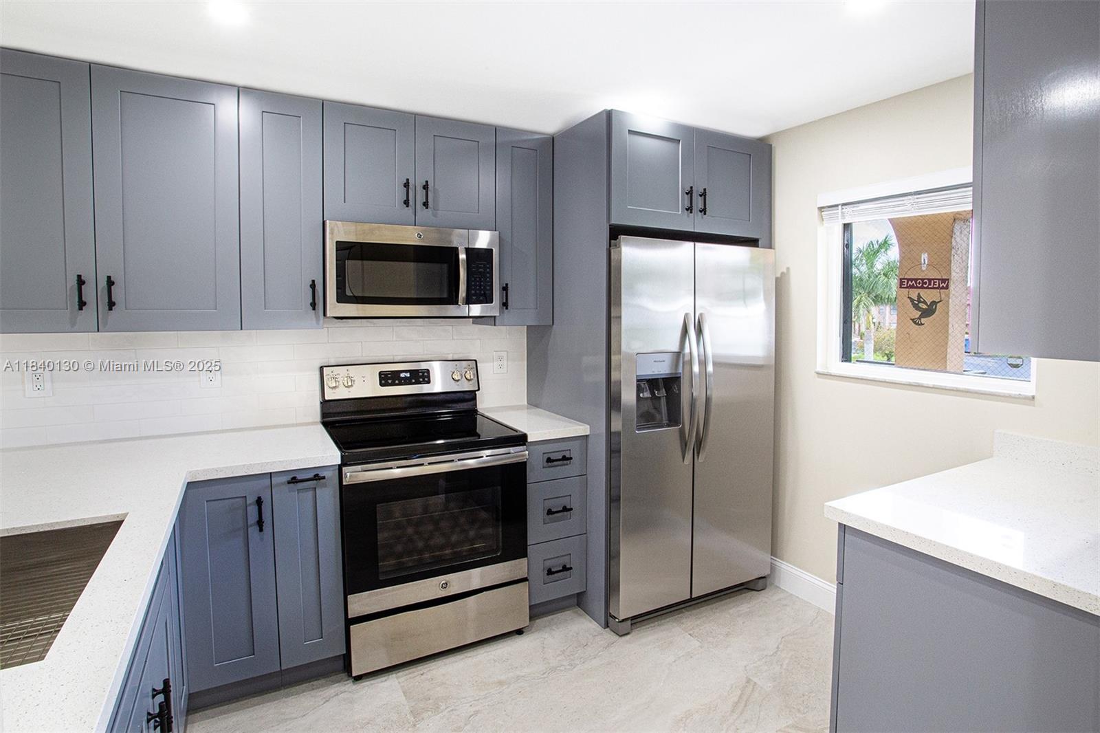 9431 Boca Cove Circle, Unit 1009 Boca Raton, FL 33428 - Photo 3 of 30 a kitchen with stainless steel appliances granite countertop a stove a refrigerator and a microwave
