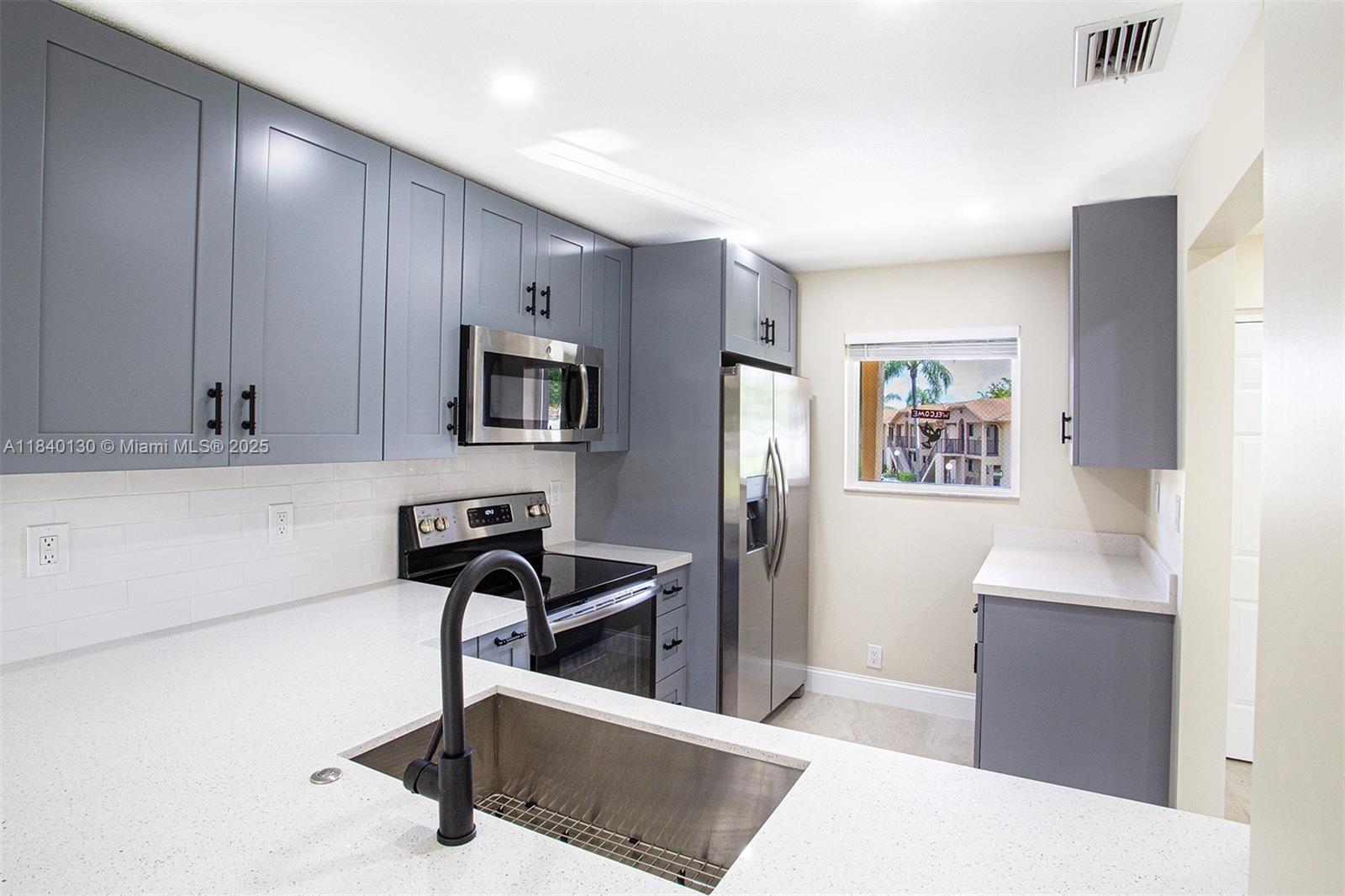 9431 Boca Cove Circle, Unit 1009 Boca Raton, FL 33428 - Photo 4 of 30 a kitchen with stainless steel appliances a sink a stove a refrigerator a microwave oven with cabinets and wooden floor
