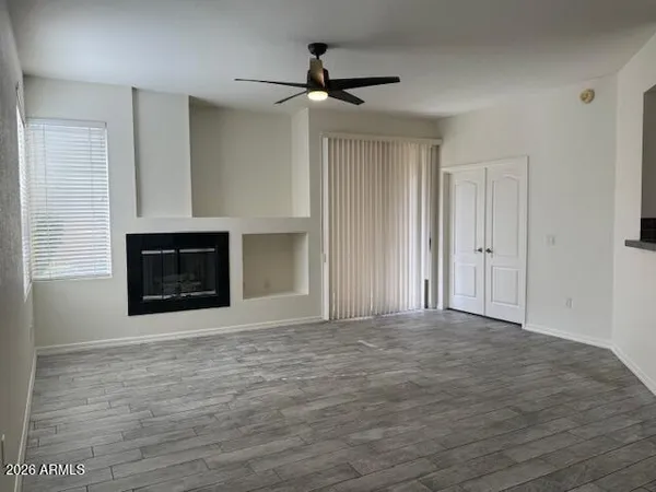 a view of empty room with a fireplace and a ceiling fan