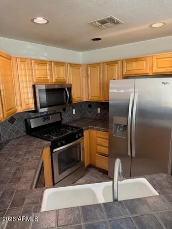 a kitchen with granite countertop a stove a sink and a refrigerator
