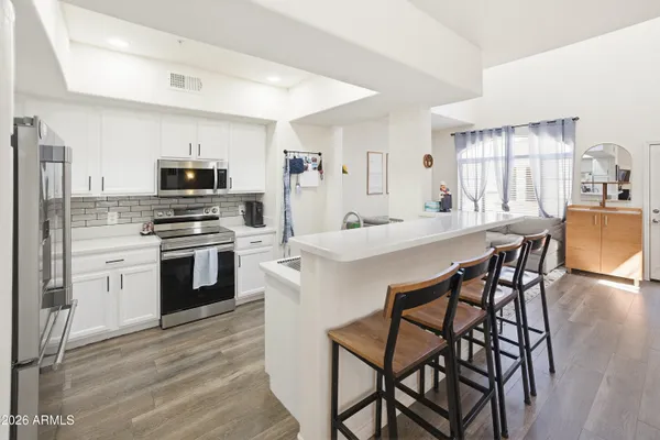 a kitchen with stainless steel appliances a kitchen island hardwood floor sink stove dining table and chairs