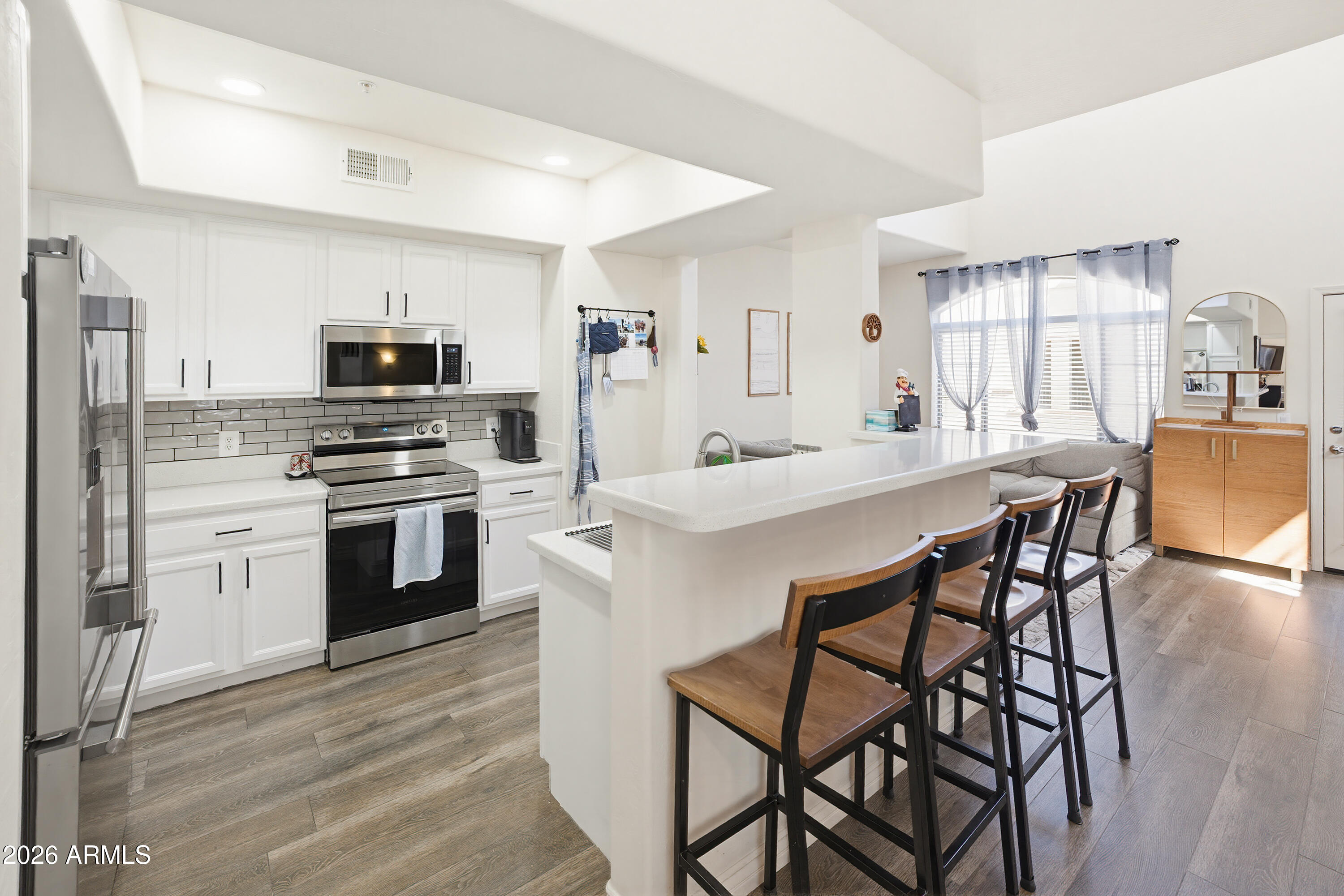 3250 West Greenway Road, Unit 162 Phoenix, AZ 85053 - Photo 2 of 31 a kitchen with stainless steel appliances a kitchen island hardwood floor sink stove dining table and chairs