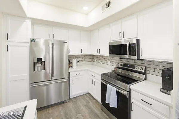 a kitchen with cabinets stainless steel appliances and wooden floor