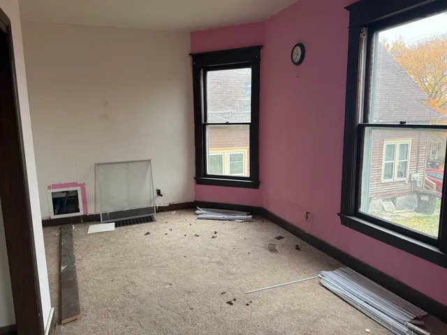 a view of an empty room with a window and wooden floor