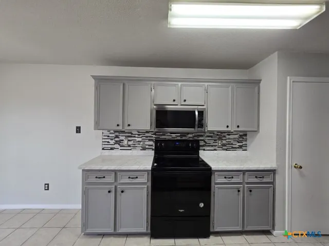 a kitchen with white cabinets and appliances