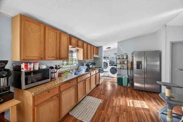 a kitchen with stainless steel appliances granite countertop wooden cabinets a stove a sink and dishwasher with wooden floor