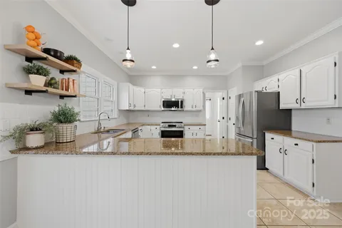 a large kitchen with granite countertop a large counter top appliances and cabinets