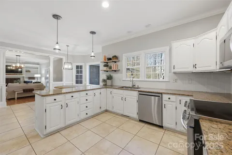 a kitchen with granite countertop white cabinets white appliances with a sink and dishwasher