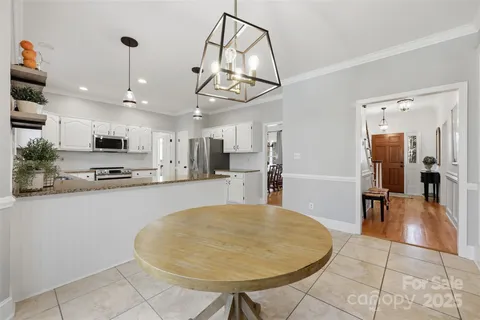 a view of a kitchen with kitchen island stainless steel appliances refrigerator stove dining table and chairs